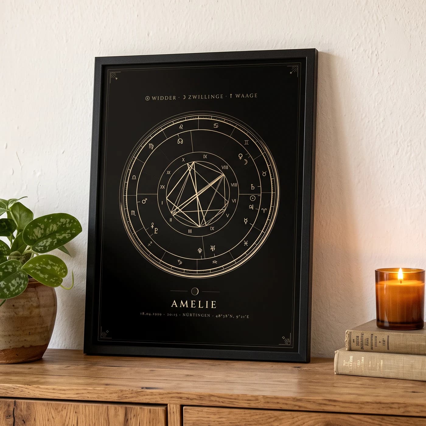 Das gerahmte Geburtsrad-Poster auf einer Holzkommode, daneben Pflanze, Kerze und Bücher